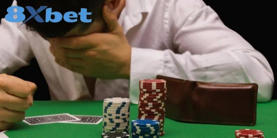 Người chơi ôm mặt thất vọng bên chồng chip và ví tiền sau khi thua cược